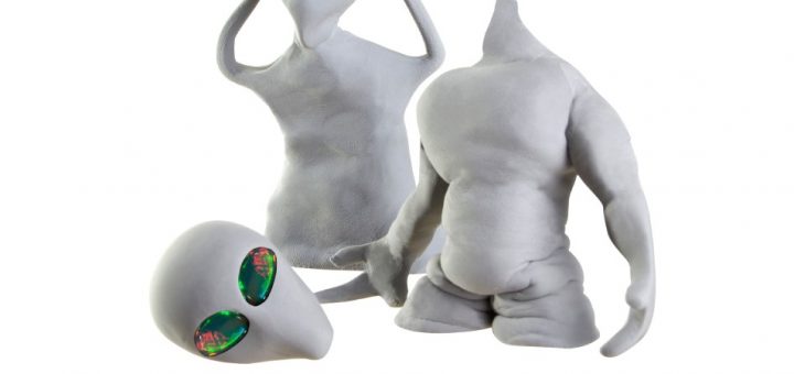 Two clay figures of gray aliens. One appears to be adjusting its head, while the other’s head is detached from its body.