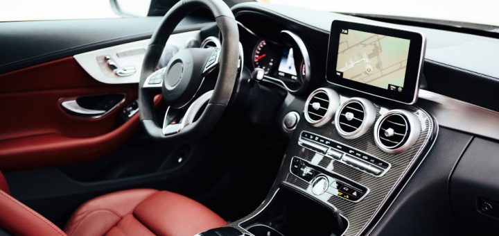 The clean and polished interior of a vehicle, featuring a luxurious red driver's seat and touch screen navigation.