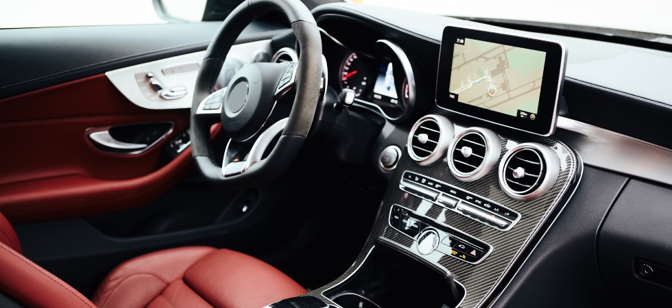 The clean and polished interior of a vehicle, featuring a luxurious red driver's seat and touch screen navigation.