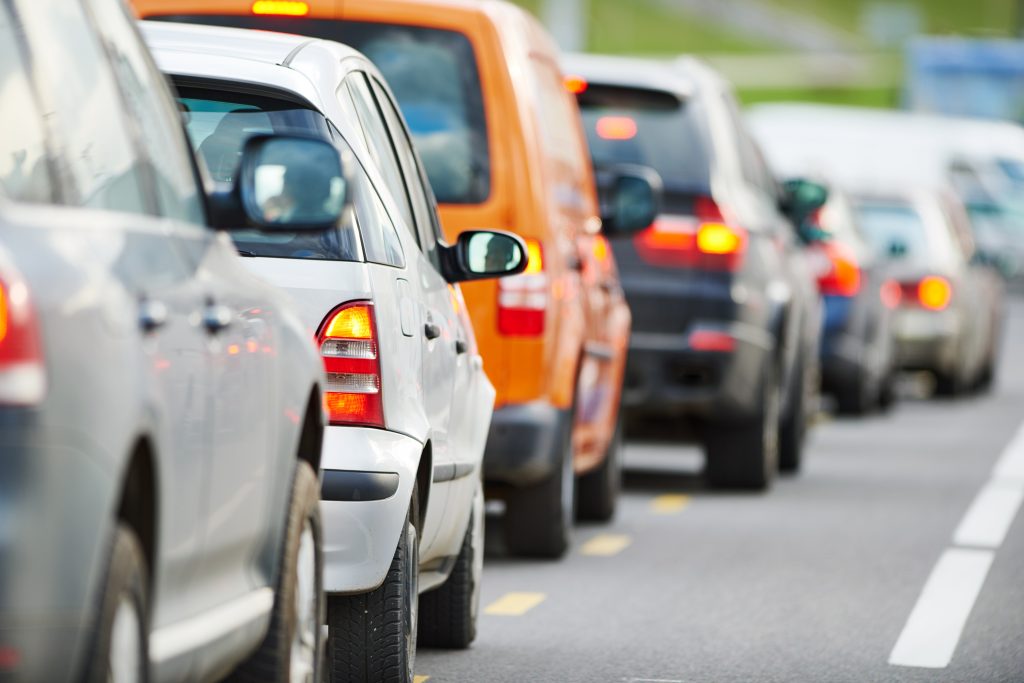 Over half a dozen cars of different brands, models, and colors lined up bumper-to-bumper in heavy traffic.