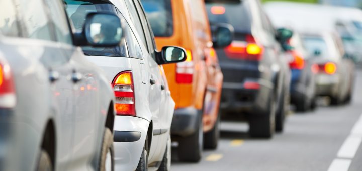 Over half a dozen cars of different brands, models, and colors lined up bumper-to-bumper in heavy traffic.