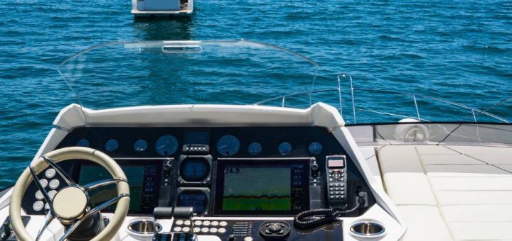 The navigation system of a boat with two screens and a radio. There are four other vessels of varying sizes in the water ahead.
