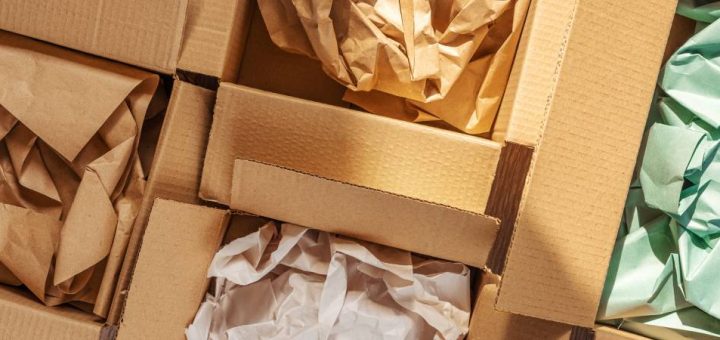 A close-up view shows four open cardboard boxes that contain crumpled brown, white, and green paper.