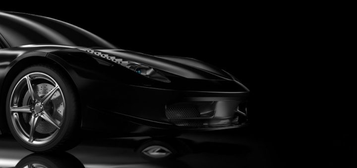 A sleek, black car with a blank plate number and modified rims sits against a black background, reflecting light.