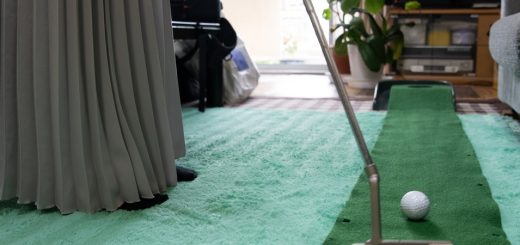 A woman practices her golf putts at home, hitting balls on a mat that looks like a golf green and leads to a hole.