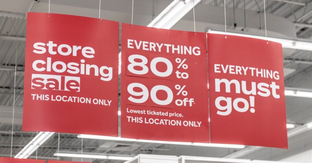 Red marketing banners inside a business hanging from the ceiling. The banners have white lettering for a sale.