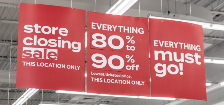 Red marketing banners inside a business hanging from the ceiling. The banners have white lettering for a sale.