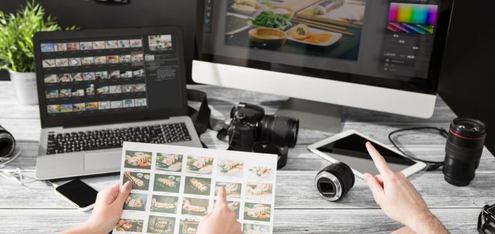 Two sets of hands both pointing at photographs. There is also a computer screen with editing software on it.