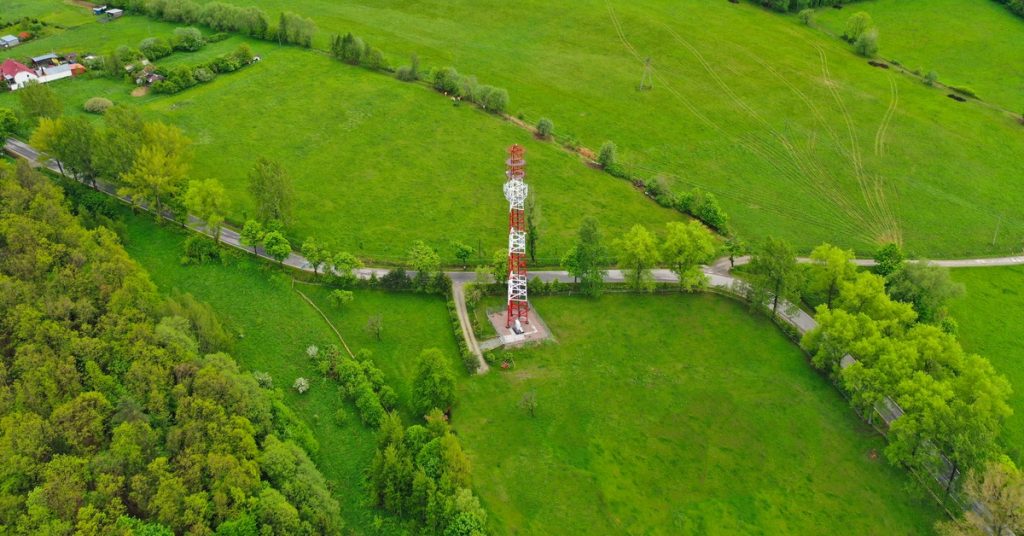An aerial view of rural land with a tower structure in a small pocket of the land, away from houses or barns.