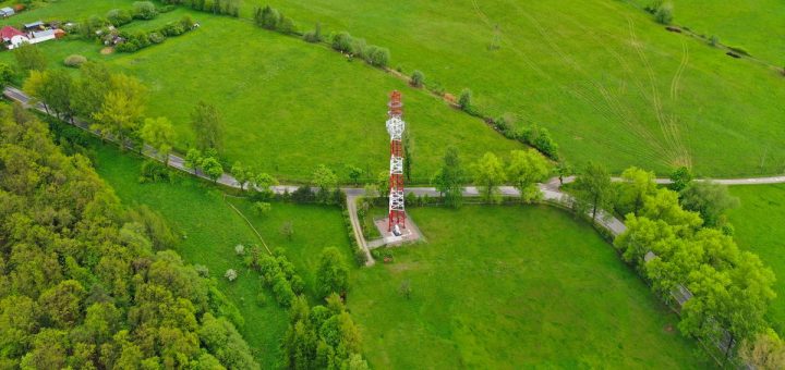 An aerial view of rural land with a tower structure in a small pocket of the land, away from houses or barns.