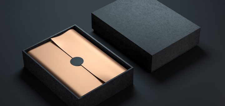 A black rigid box with the top next to the bottom part of the package. Inside is gold paper with a black circle sticker in the center