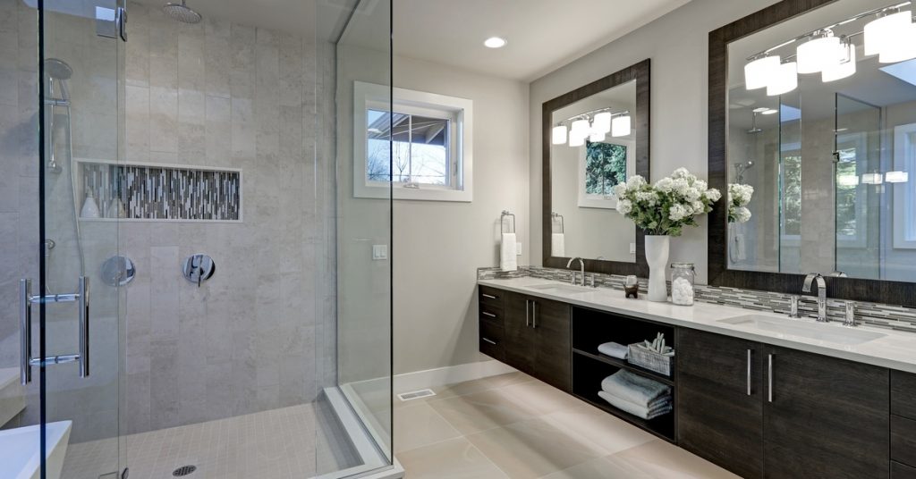 A bathroom with a large walk-in shower, beige floor tiles, two sinks, large mirrors, ample light, and white walls.