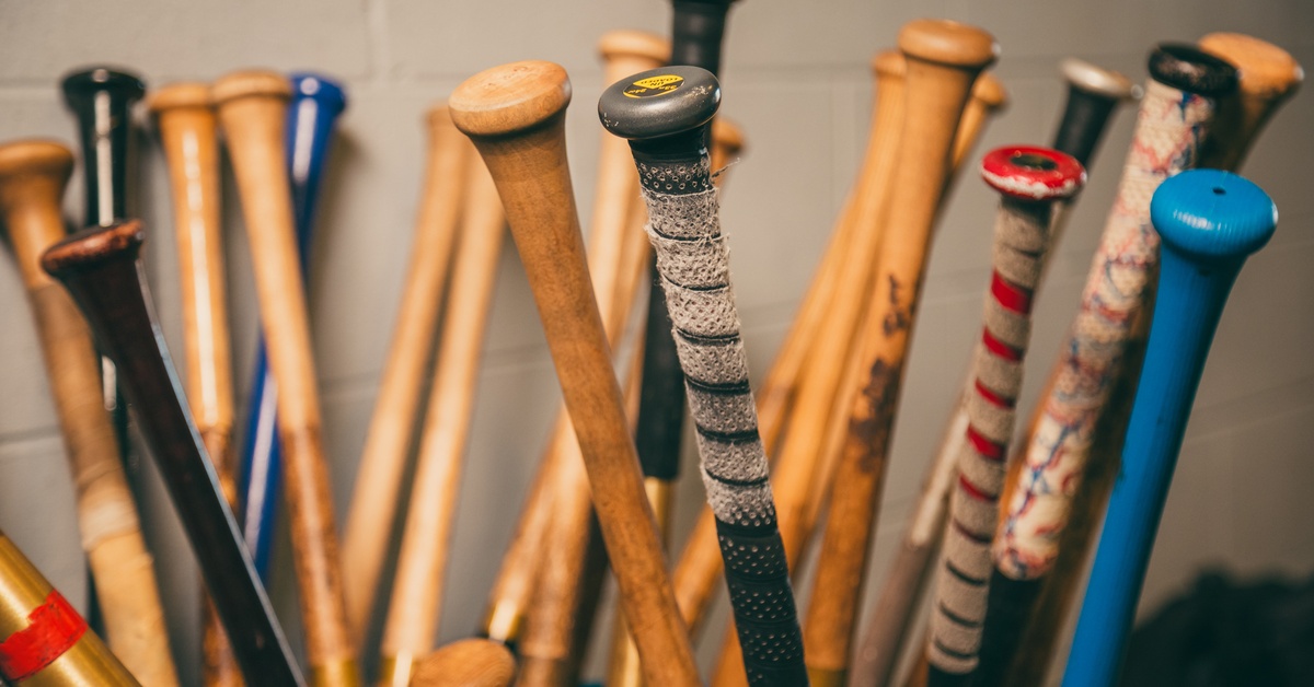 A group of wooden baseball bats arranged side by side, showing smooth finishes and varying wood grain textures.