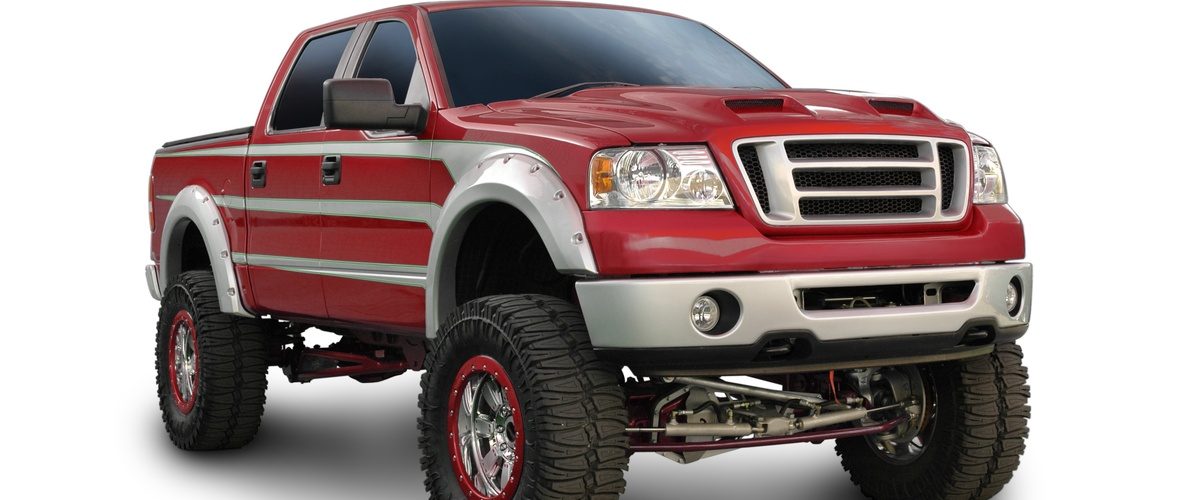 A red truck with silver trim is parked against a solid white background. The truck is clearly lifted with a greater height.