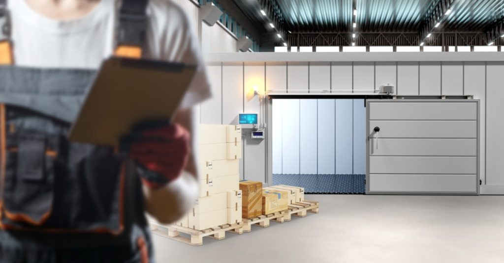 A person is holding a clipbord while they are standing in an industrial warehouse environment.