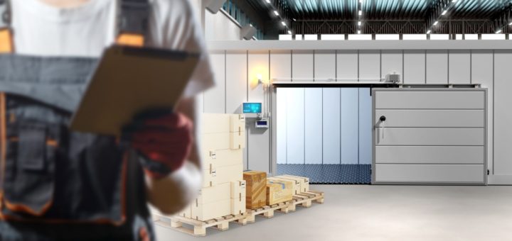 A person is holding a clipbord while they are standing in an industrial warehouse environment.