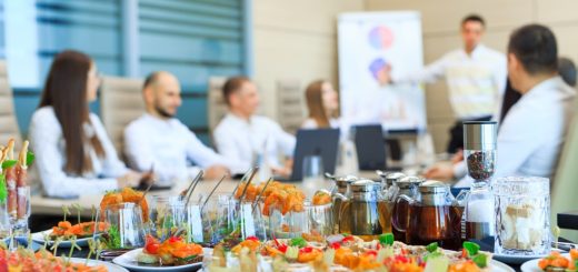 A close-up of a table in a business office meeting room filled with catered finger foods and drinks.