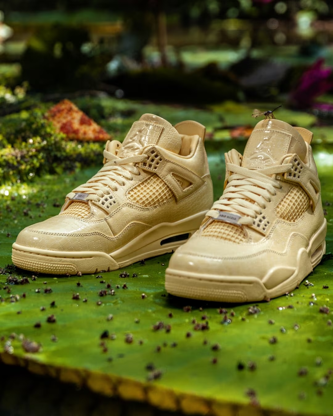 Pair of Air Jordan 4 x J Balvin sneakers toe-to-toe on a leafy green backdrop