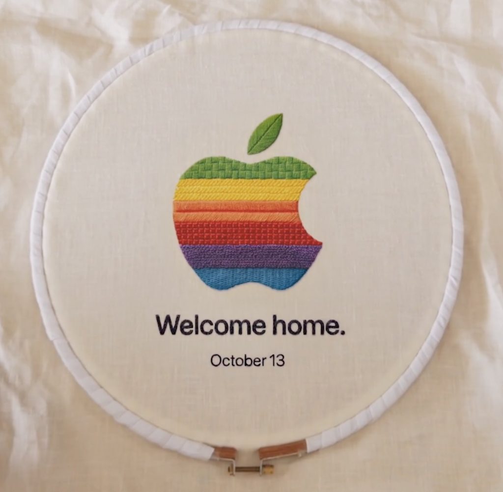 Apple’s “Welcome Home” event teaser showing an embroidered rainbow Apple logo with the date October 13