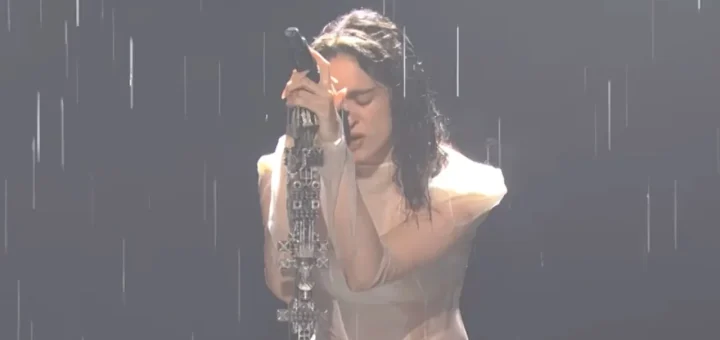 Rosalía performs “Magnolias” in the rain on SNL, head bowed against a microphone on an ornate stand