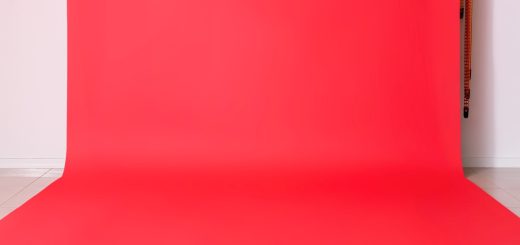 A vibrant red photo backdrop hanging against a white wall all the way down to the floor in a brightly lit room.